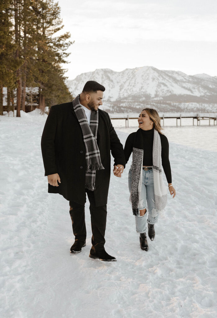 couple walking in the snow in south lake tahoe while looking at each other and smiling