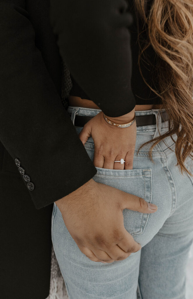 woman showing ring while putting her hand in her jean pocket, and man grabbing her butt