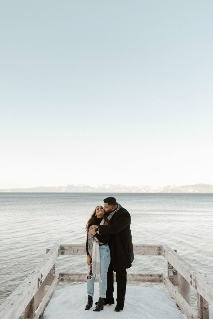 couple hugging on a snowy dock in south lake tahoe in the winter