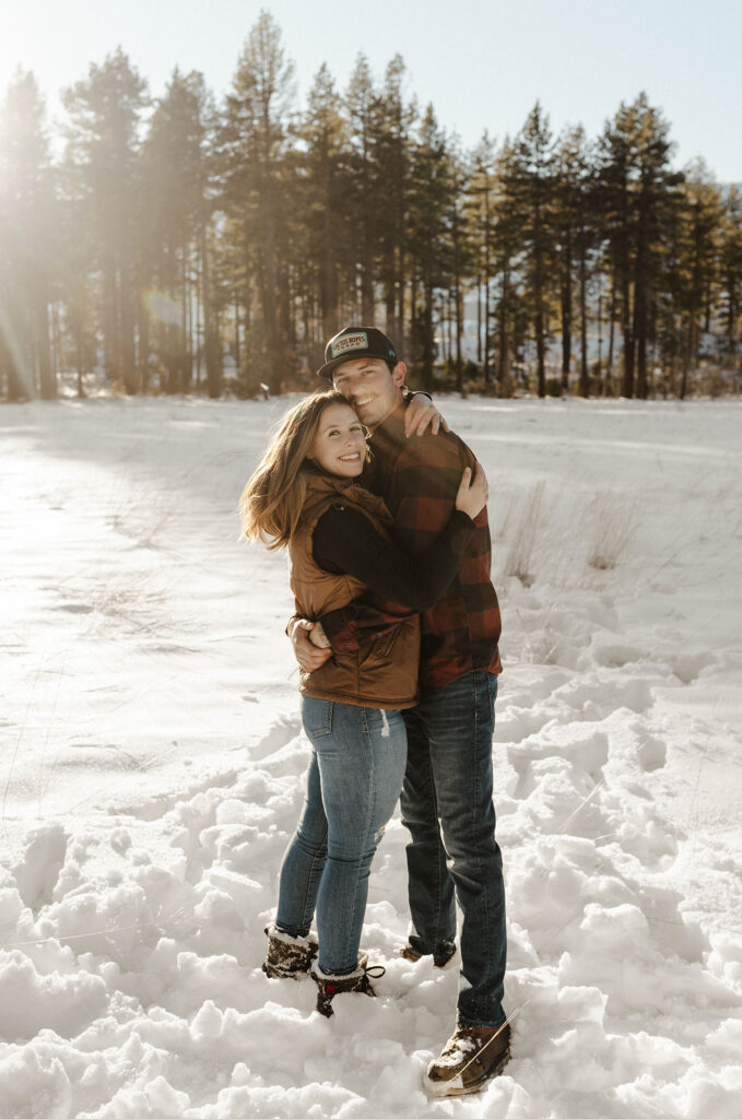 couple smiling at the camera standing in the snow in the winter in lake tahoe