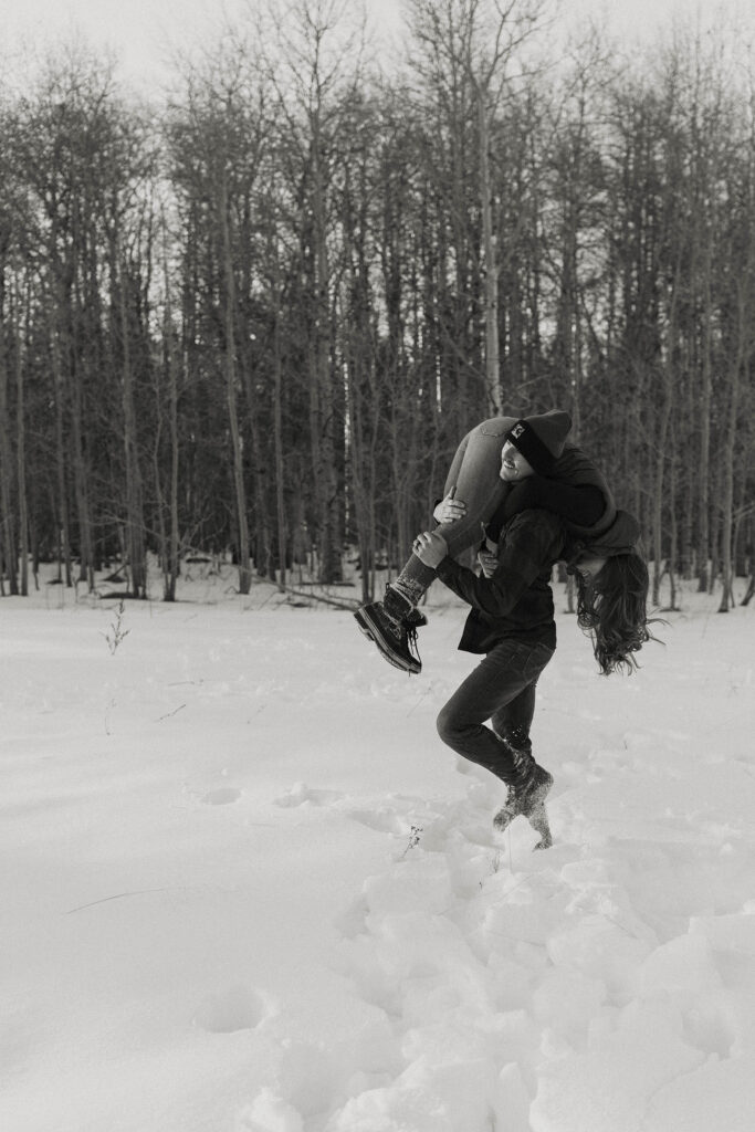 man throwing woman over his shoulder like a bag of potatoes in the snow