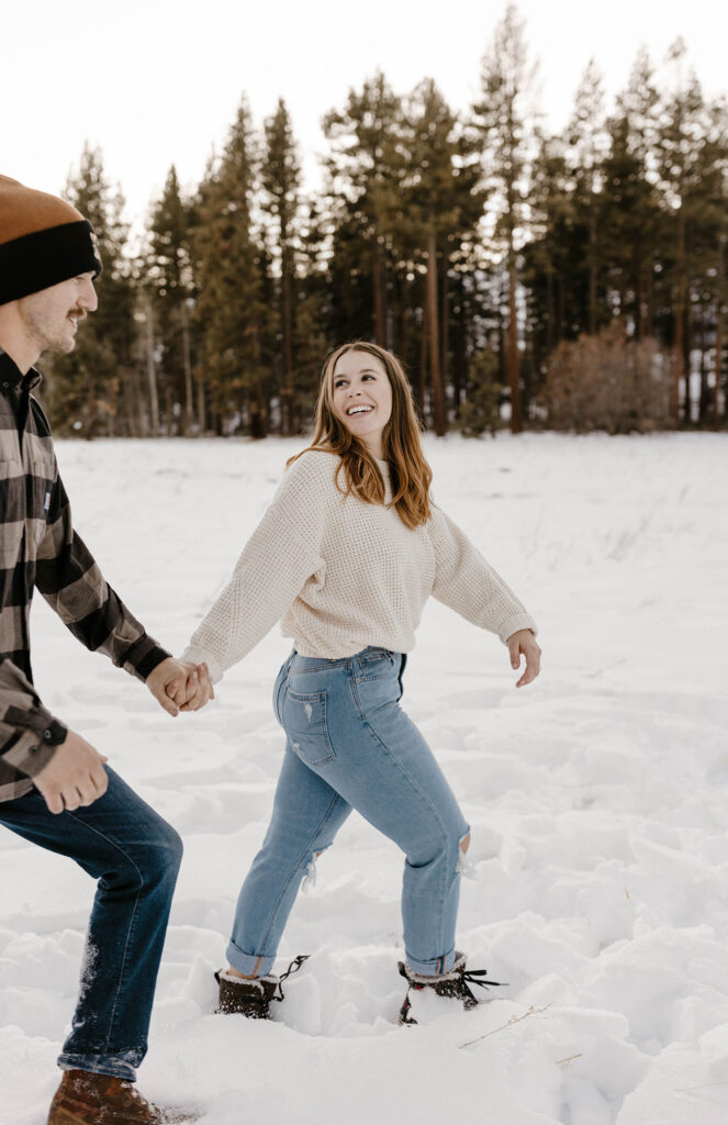 couple walking in the snow smiling in lake tahoe in the winter