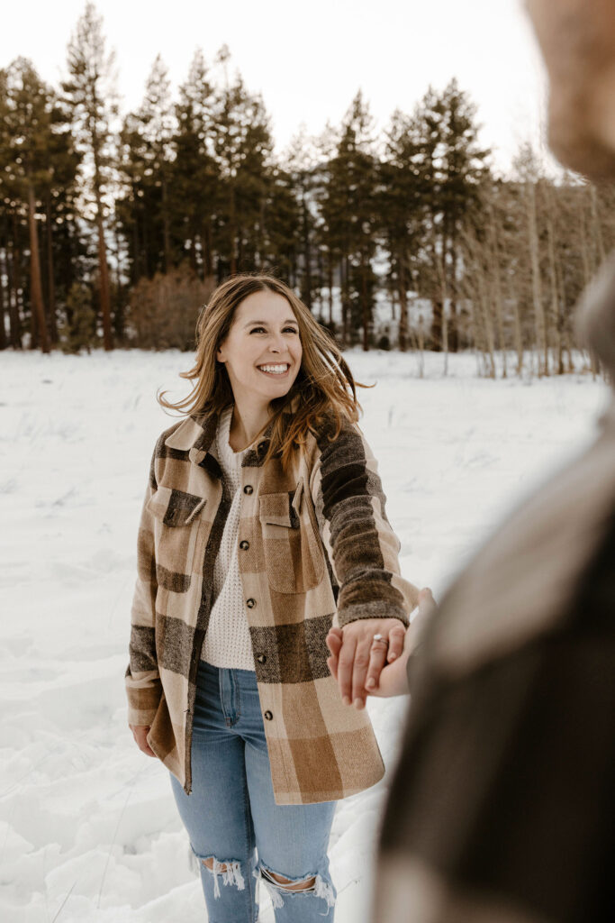 woman holding mans hand smiling in the snow in lake tahoe