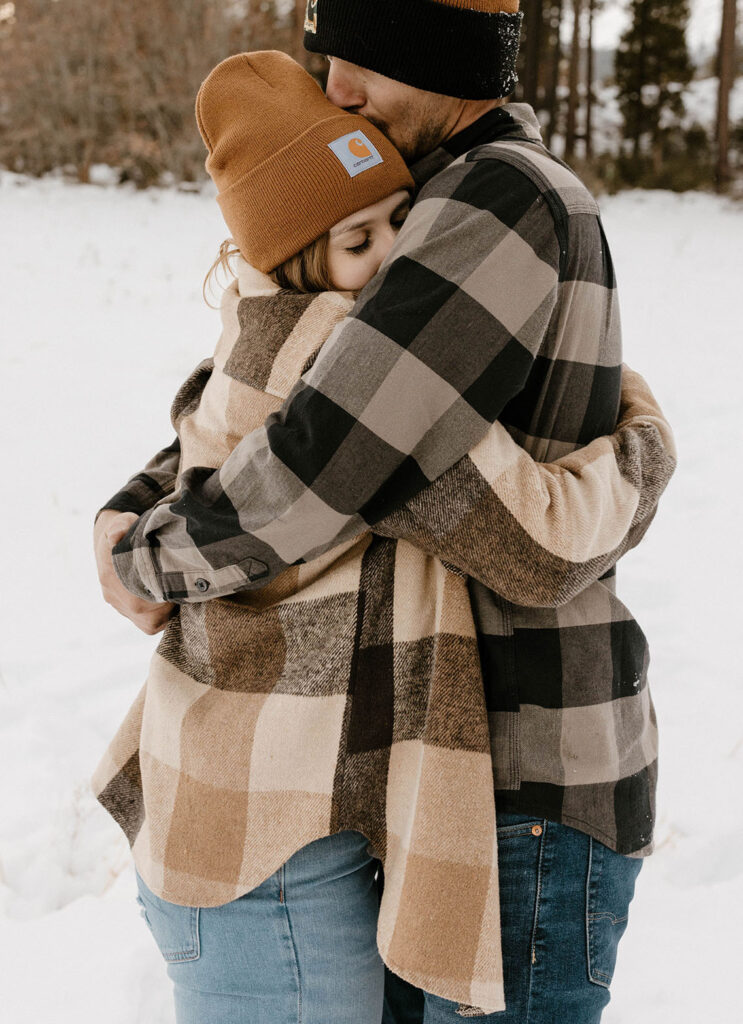couple hugging wearing beanies and plaid in the winter in lake tahoe