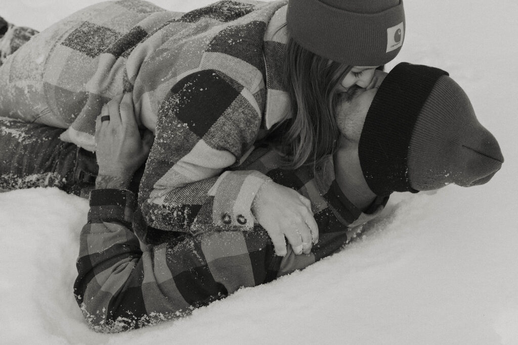 couple kissing while laying in the snow in lake tahoe