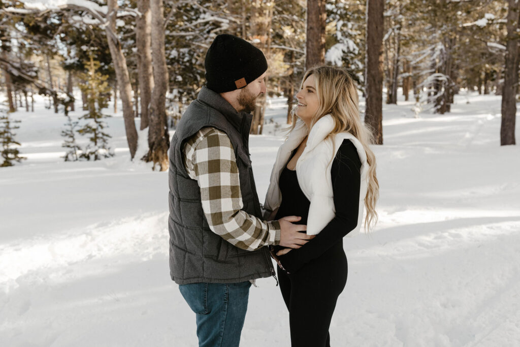 maternity couple smiling and holding belly in lake tahoe