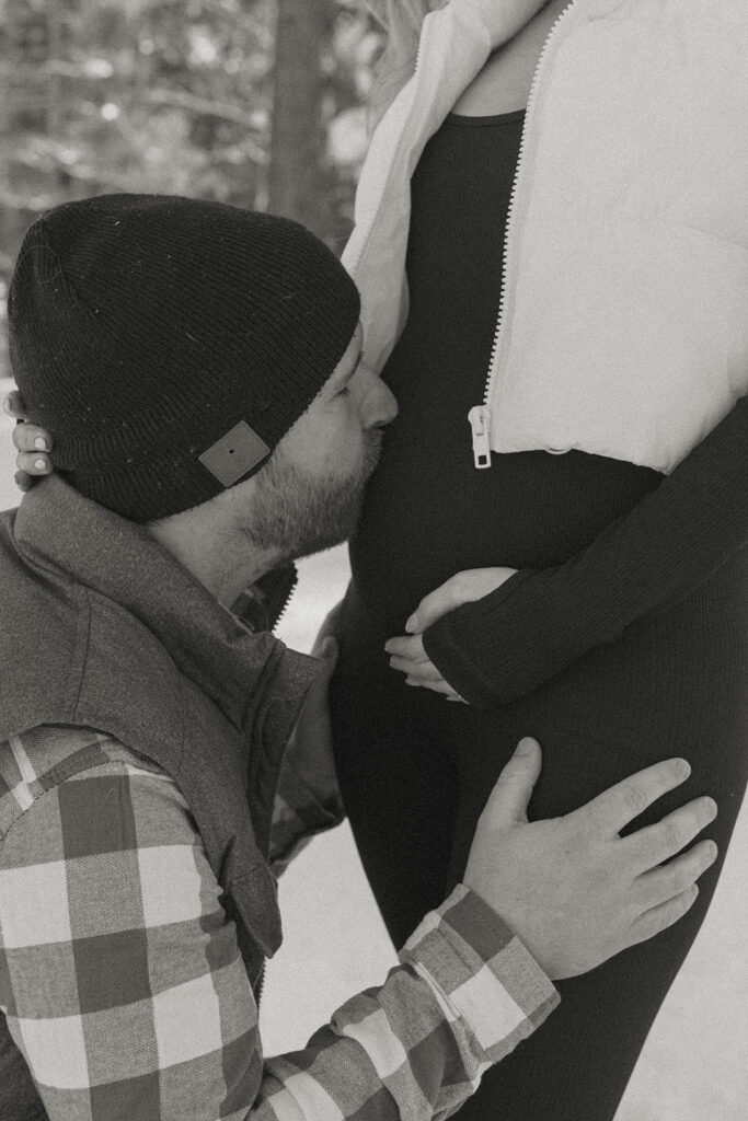 close up of man kissing pregnant woman's belly