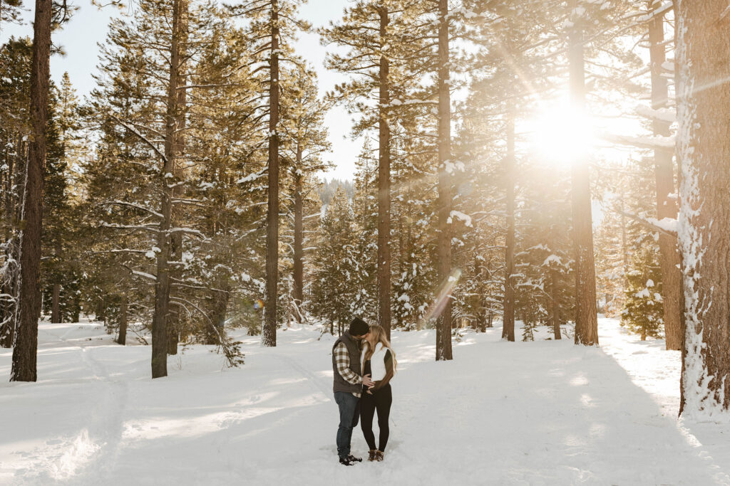 maternity couple kissing in the snow in lake tahoe from a distance