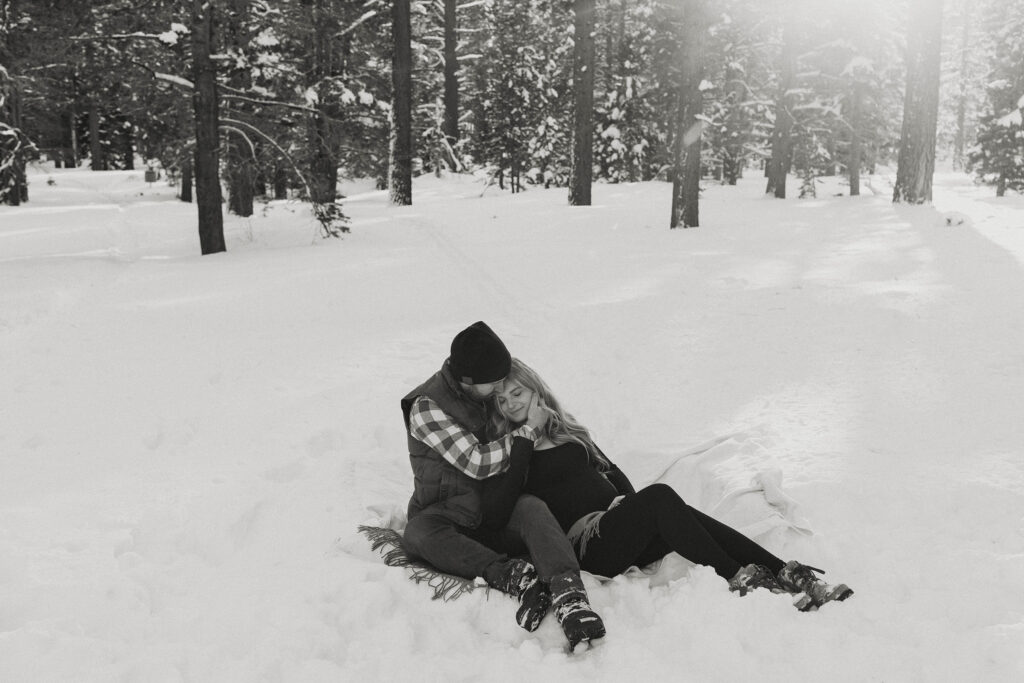 maternity couple laying in the snow hugging in lake tahoe