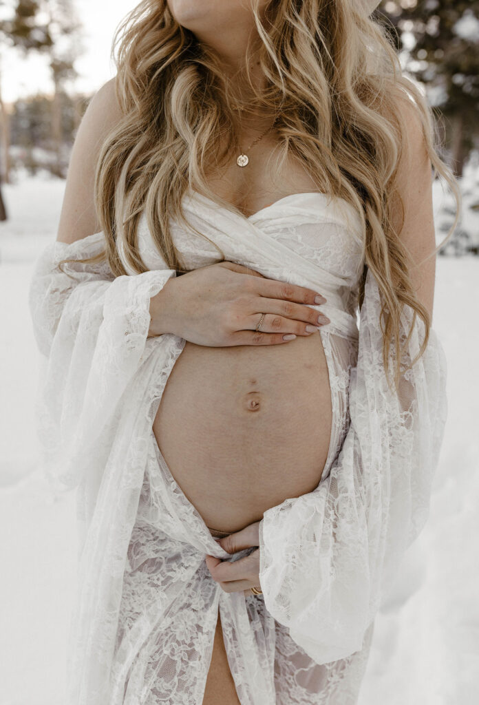 pregnant woman showing her belly wearing a white lace dress