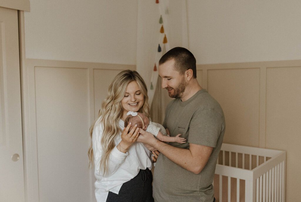 Couple holding baby together while smiling at her inside home