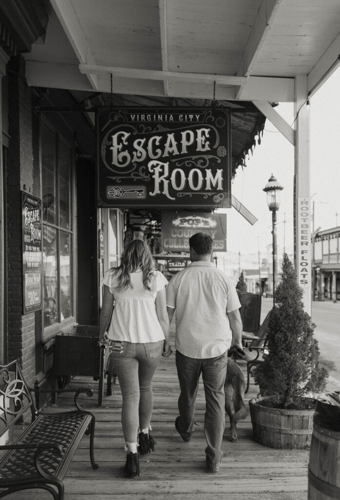 Engagement couple holding hands and walking down wooden walkway at downtown virginia city