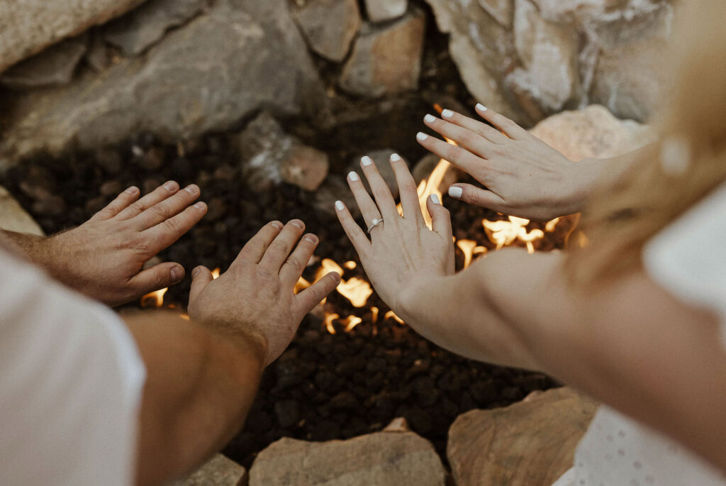 Close up of engagement couples warming hands near fire with engagement ring in virginia city