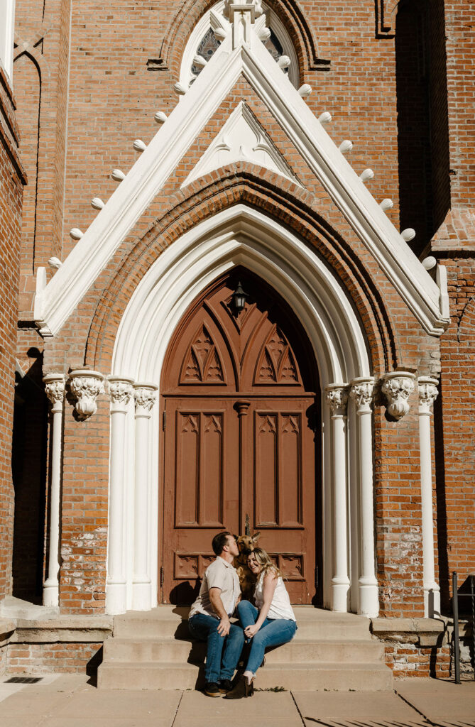 Engagement couple sitting on steps in front of chapel in virginia city