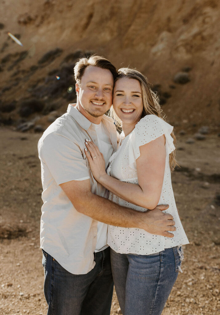 Engagement couple holding each other while smiling at camera outside virginia city