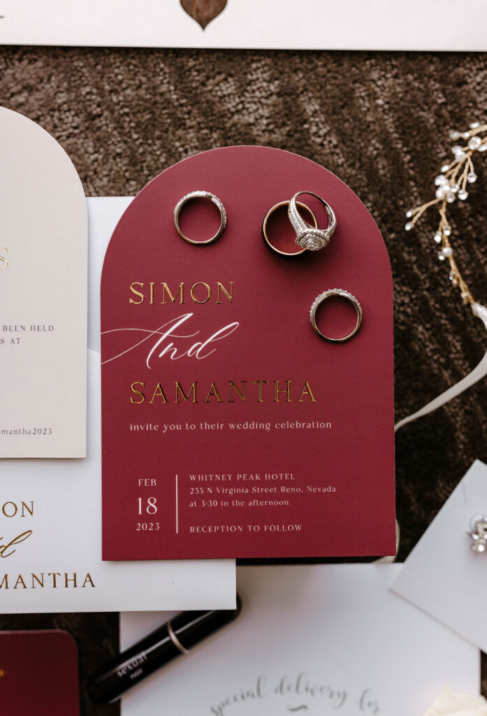 maroon wedding invites and rings laid out for a winter wedding at the whitney peak hotel