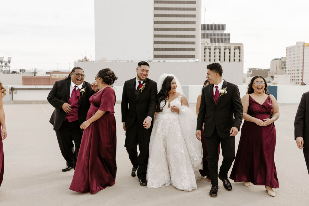 bridal party in maroon colors walking and laughing at a winter wedding at the whitney peak hotel