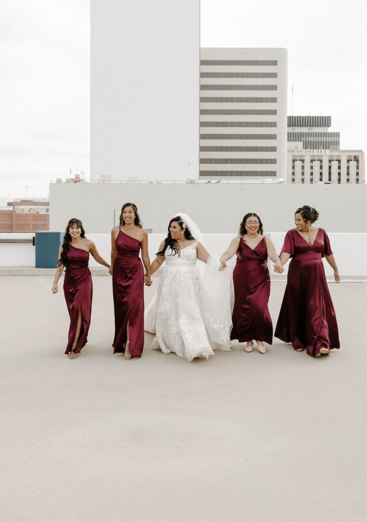 bridesmaids walking and laughing in maroon dresses at a winter wedding at the whitney peak hotel