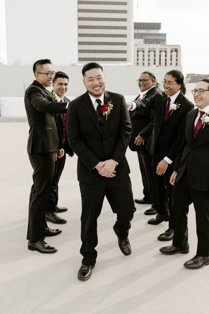 groomsmen shoving the groom and laughing at a winter wedding at the whitney peak hotel