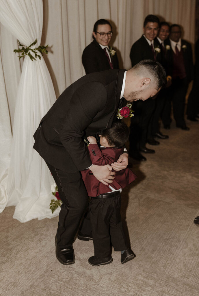 boy hugging the groom during the ceremony at the whitney peak hotel