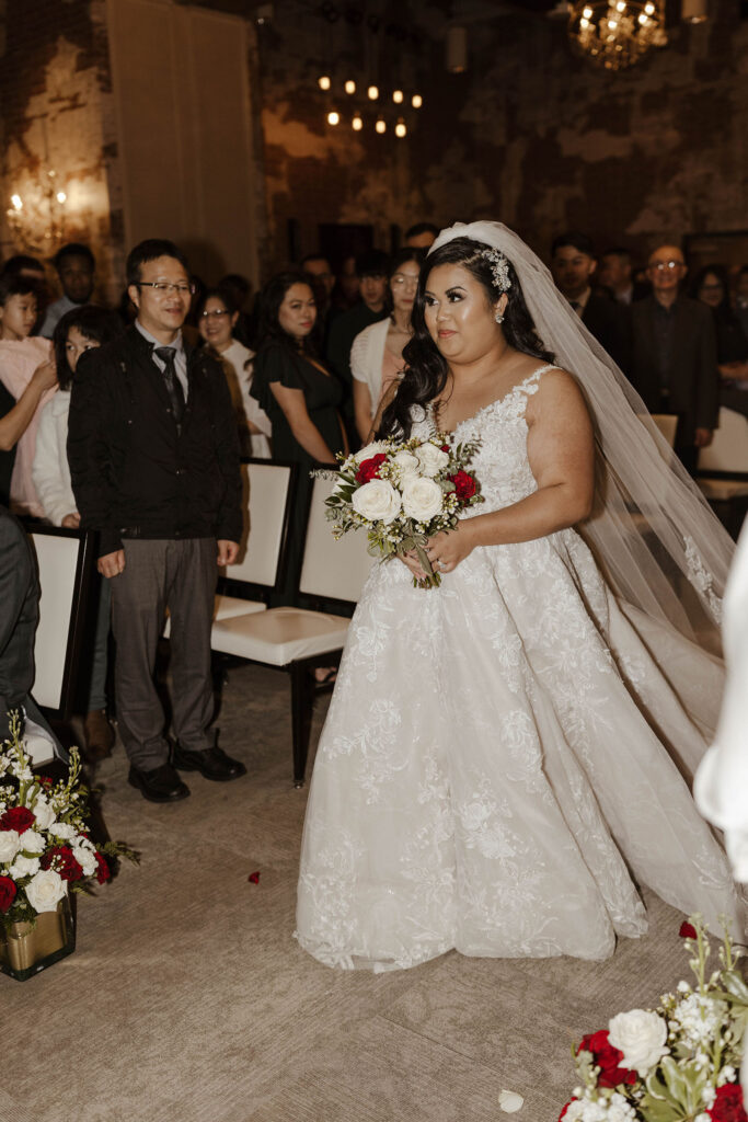 bride walking down the aisle holding flowers during her ceremony at the whitney peak hotel