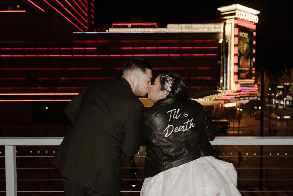 bride and groom kissing wearing a til death leather jacket at the whitney peak hotel