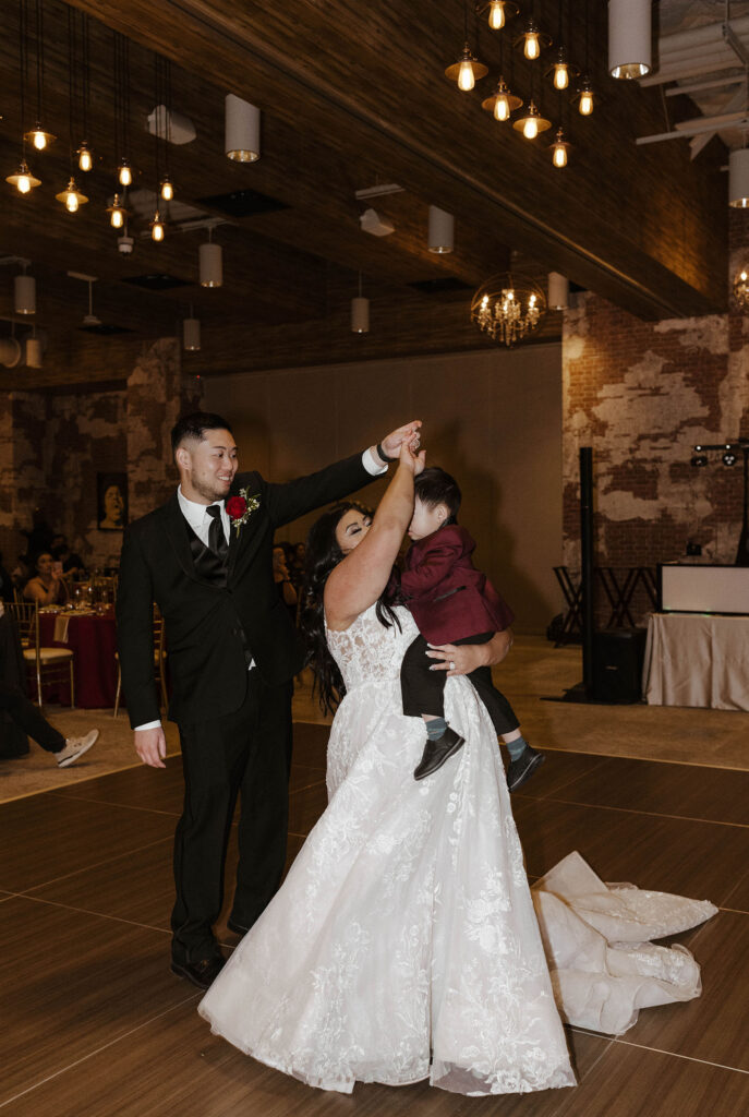 bride and groom dance together with their son at their wedding reception at the whitney peak hotel