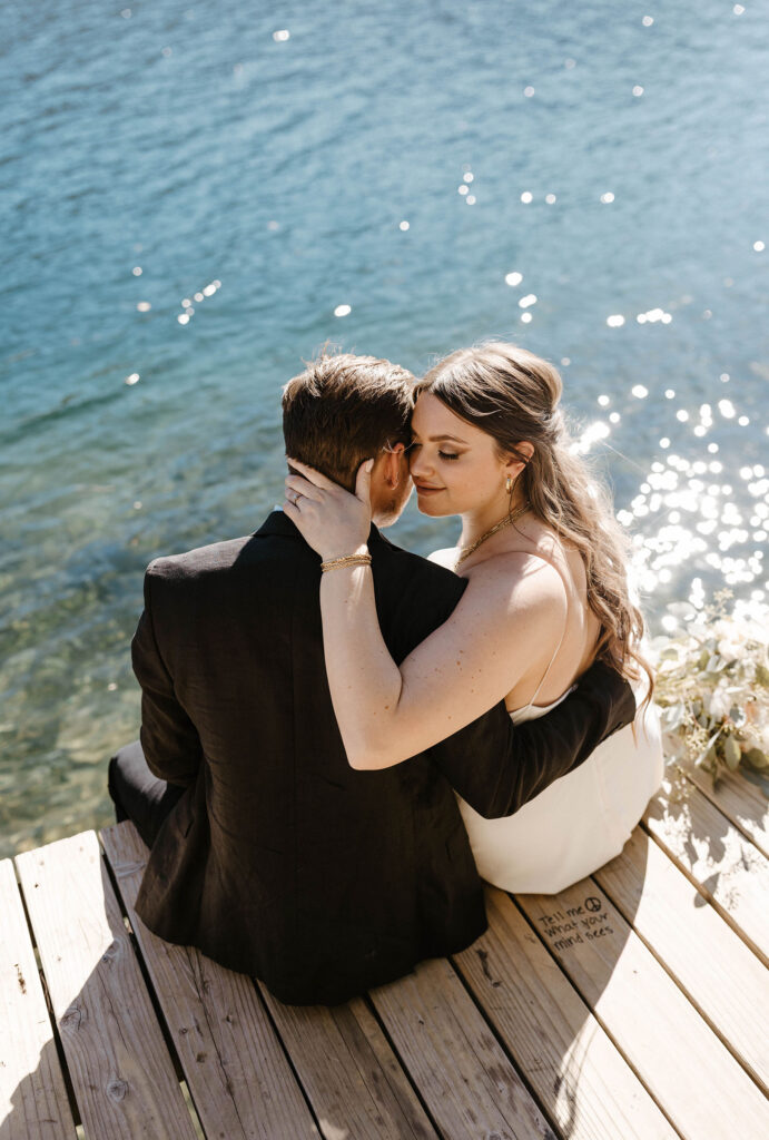 Elopement couple sitting on dock at Donner lake holding each other