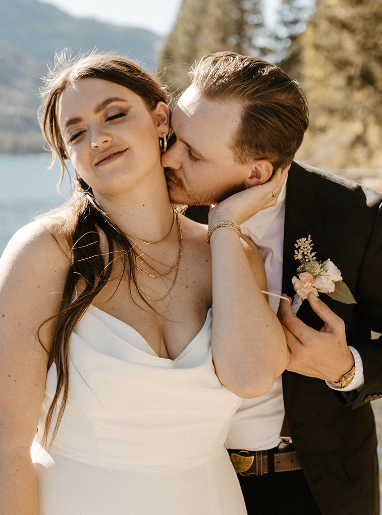 Husband kissing wife's neck while she smiles with eyes closed at Donner lake