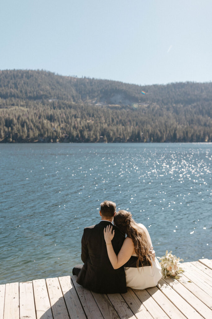 Elopement couple sitting on dock together with arms around each other at Donner lake