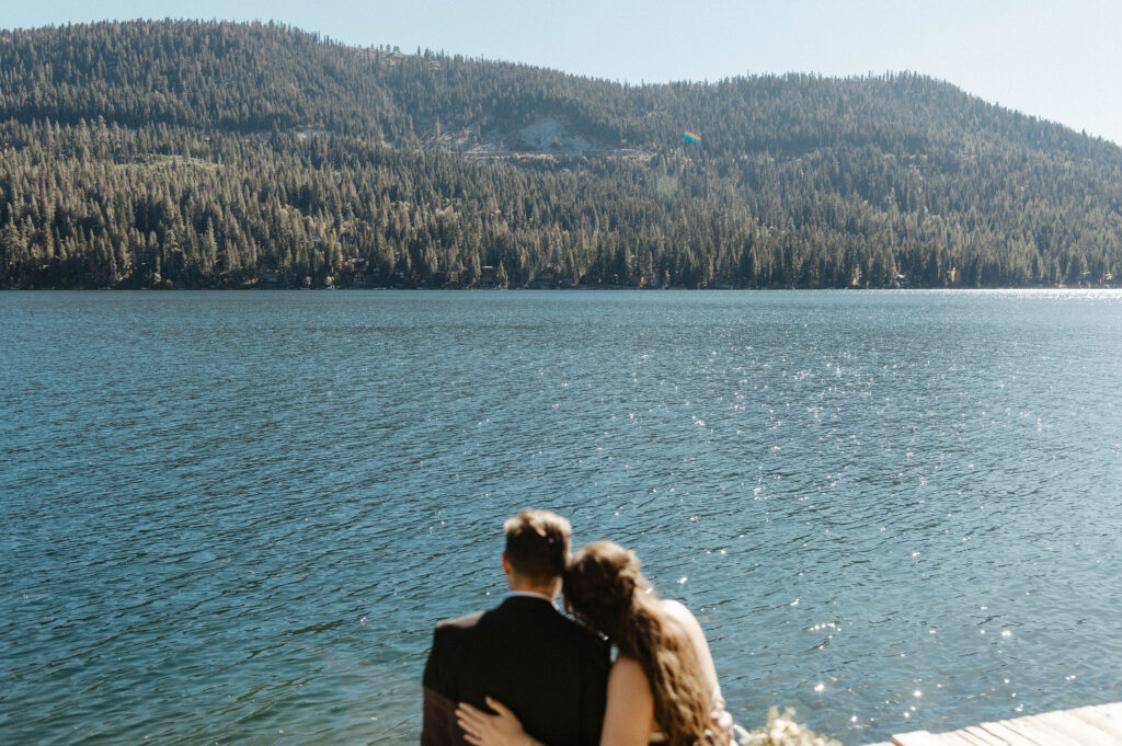 Elopement couple sitting on dock together looking out over Donner lake and mountains