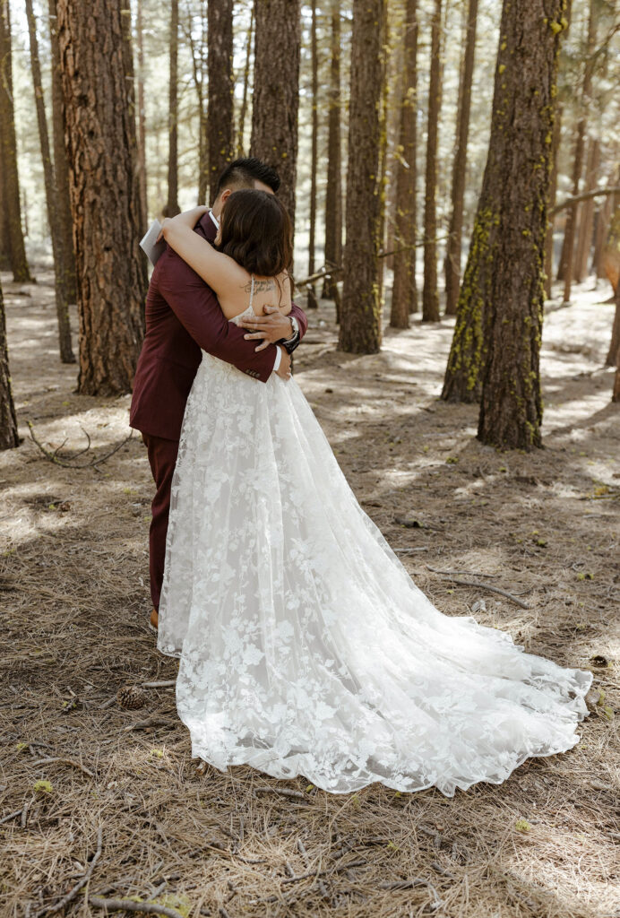Wedding groom hugging bride while surrounded by tall trees at Chalet View Lodge