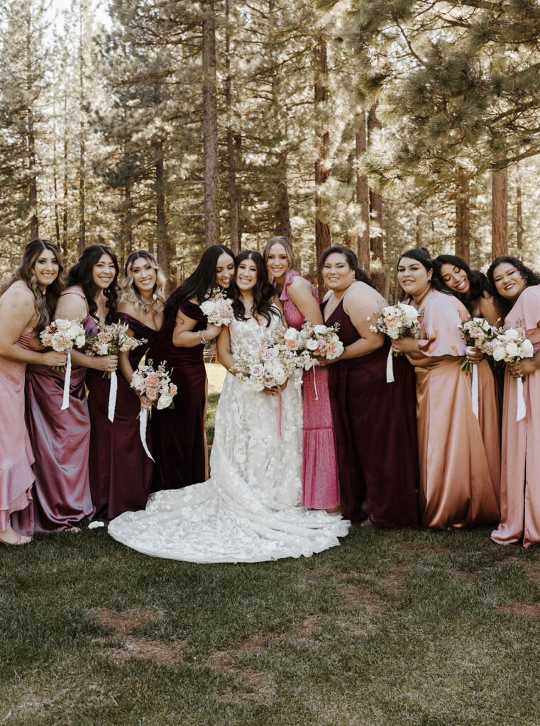 Wedding bride smiling with bridesmaids while all are holding floral bouquets and looking at camera at Chalet View Lodge