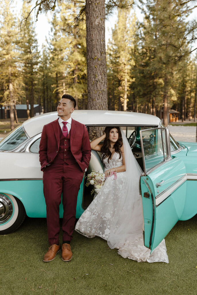 Wedding groom smiling as bride sits in classic teal and white car with the door open at Chalet View Lodge