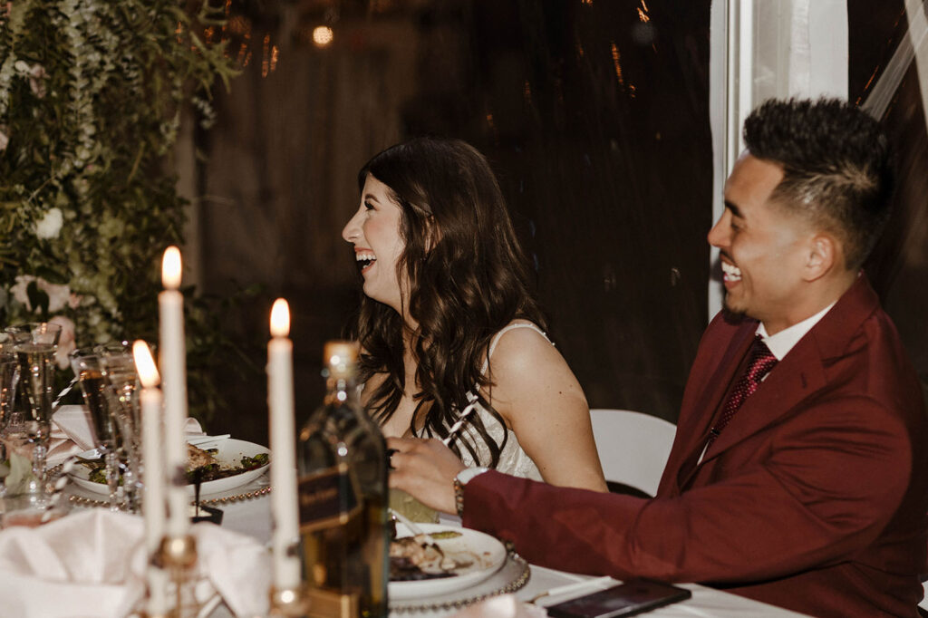Wedding bride laughing while eating dinner with groom during reception at Chalet View Lodge