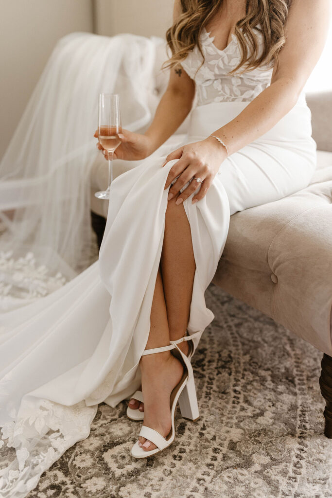Wedding bride holding glass with hand on her knee while sitting on couch inside at little bear creek ranch