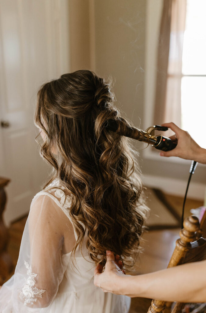 Wedding bride getting hair curled while getting ready inside at little bear creek ranch