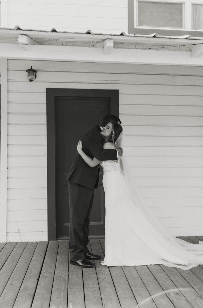 Wedding bride hugging dad during first look on wooden porch at little bear creek ranch