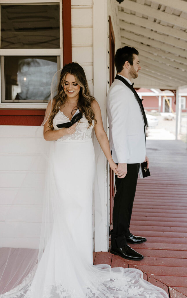 Wedding bride smiling while holding hands with groom around corner and reading vows at little bear creek ranch