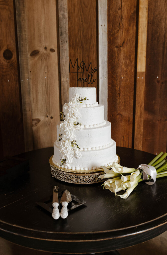 Wedding cake with white floral decorations on wooden table at little bear creek ranch