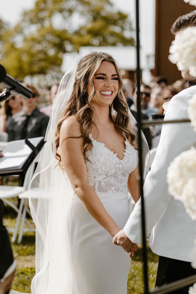 Wedding bride smiling at groom during ceremony and holding hands at little bear creek ranch