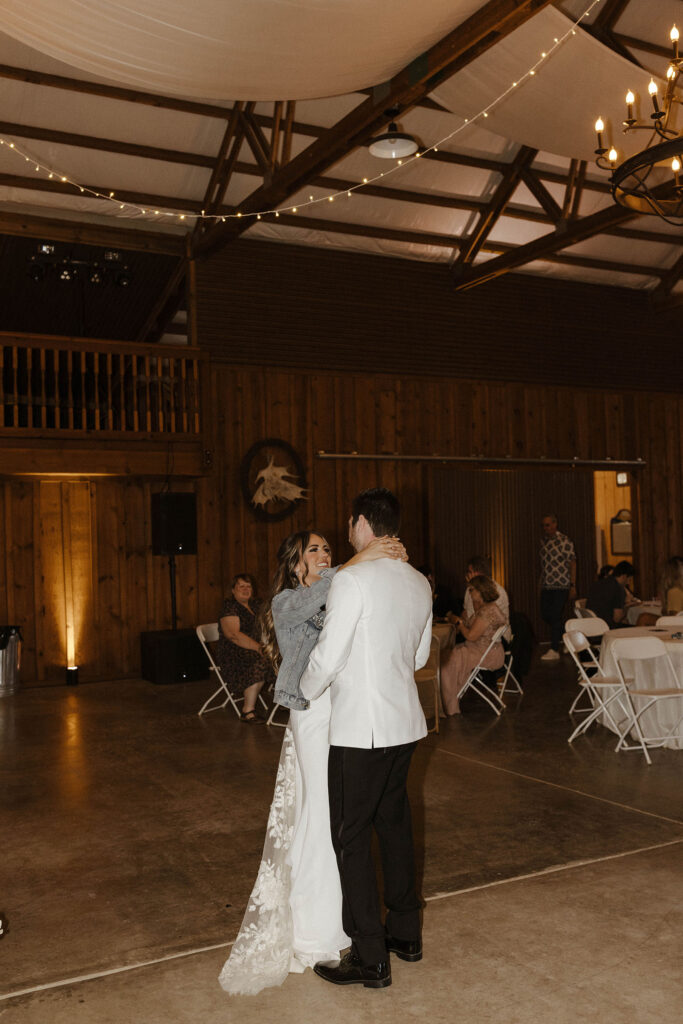 Bride smiling at groom during the wedding couple first dance while inside at little bear creek ranch