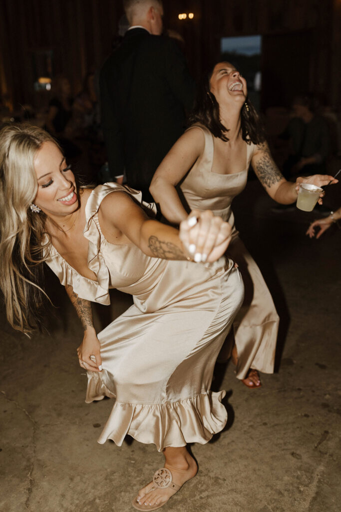 Bridesmaids dancing while laughing and holding drinks during reception at little bear creek ranch