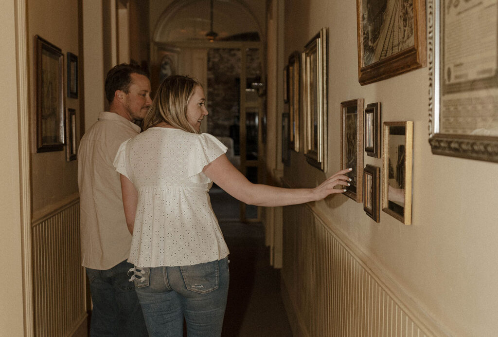 Engagement couple walking down hallway looking at pictures in virginia city