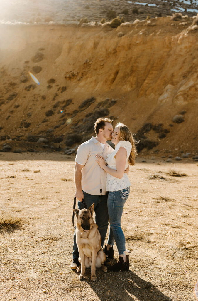 Man kissing fiancé on cheek while holding dogs leash outside virginia city