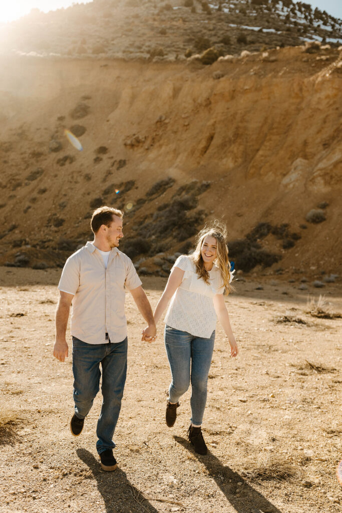 Engagement couple holding hands and walking towards camera outside at virginia city