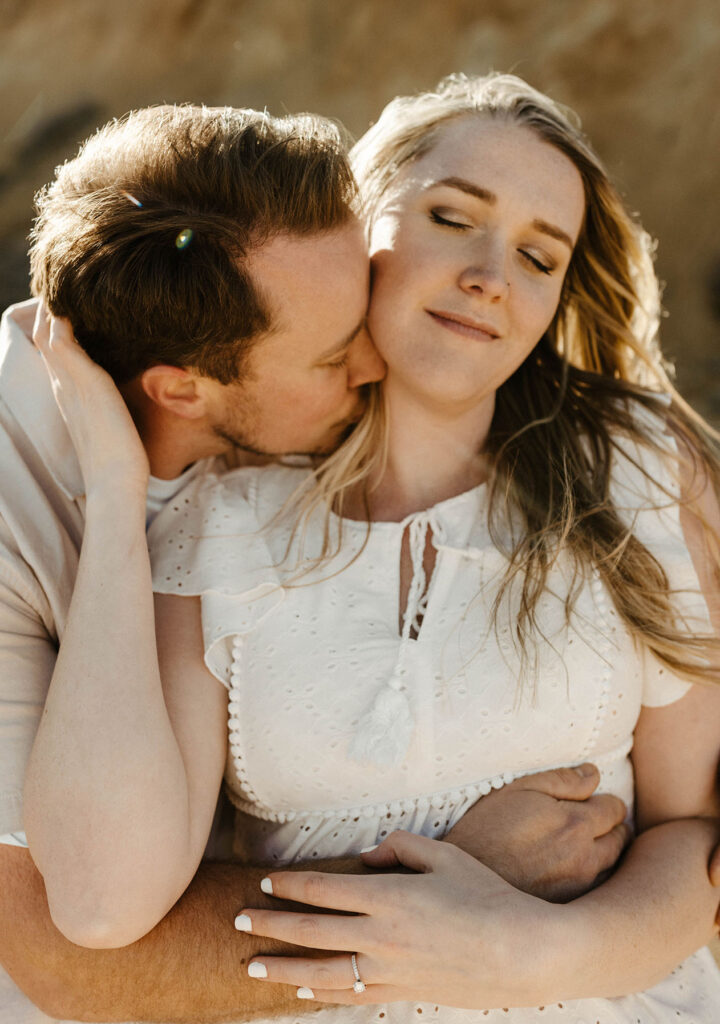 Engagement couple holding each other with eyes closed outside at virginia city
