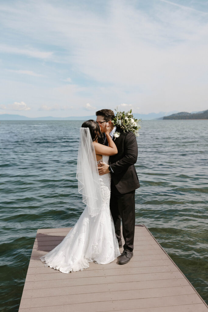 Elopement couple holding and kissing each other while standing on a pier in Lake Tahoe