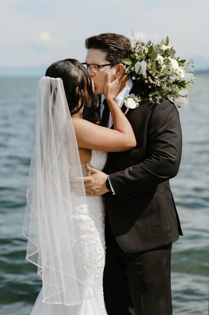 Close-up of elopement couple kissing on a pier in Lake Tahoe with lake in background