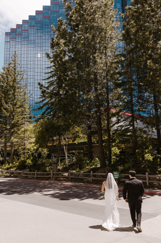 Elopement couple walking towards hotel in Lake Tahoe together with tall pine trees in front of hotel